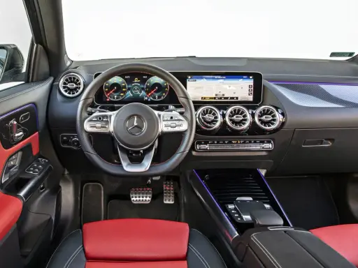 Wnętrze Mercedesa GLA 200 z czerwono-czarną tapicerką, nowoczesnym kokpitem i ekranem nawigacji.