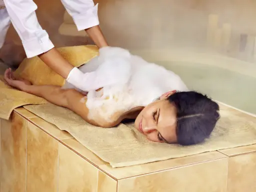 Eine Frau genießt eine Schaummassage im Hamam. Die Bedeutung von Hamam liegt in der tiefen Entspannung und Reinigung.