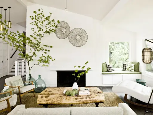 Ideas para decorar ramas secas: una rama verde decora el salón moderno con chimenea, mesa de madera y sillones.