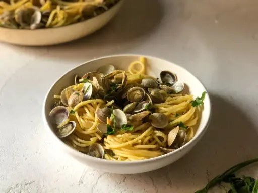 Un invitante piatto di spaghetti alle vongole, con pasta dorata e molluschi freschi, guarnito con prezzemolo.