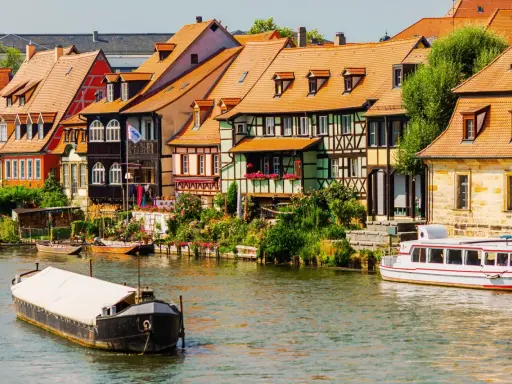 Bunte Fachwerkhäuser säumen das Wasser, Boote schaukeln sanft. Ein malerischer Anblick, der die vielen Attraktionen Bayerns widerspiegelt.