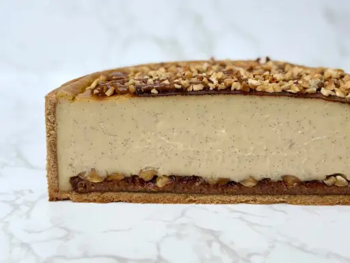 Tranche de flan praliné onctueux, garni de noisettes concassées et d'un coulis de caramel.