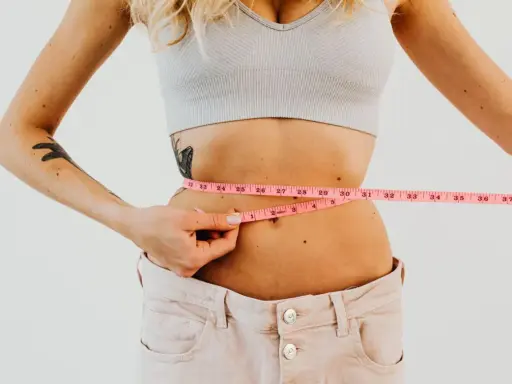 Kobieta mierzy talię centymetrem. Efekty diety 1400 kcal są widoczne.