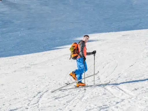 Mężczyzna na nartach z plecakiem, gotowy na skitury. Co to za przygoda?