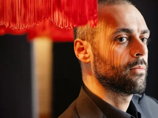Ardalan Esmaili, med ansiktet belyst av ett randigt ljus, tittar bort.