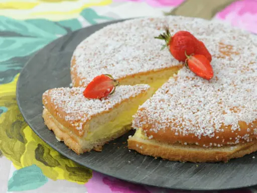 Un délicieux gâteau génoise crème pâtissière, saupoudré de sucre et garni de fraises fraîches.