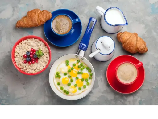 Pyszne, lekkostrawne śniadanie: owsianka z owocami, jajka sadzone z groszkiem, dwa croissanty i kawa. Idealny początek dnia!