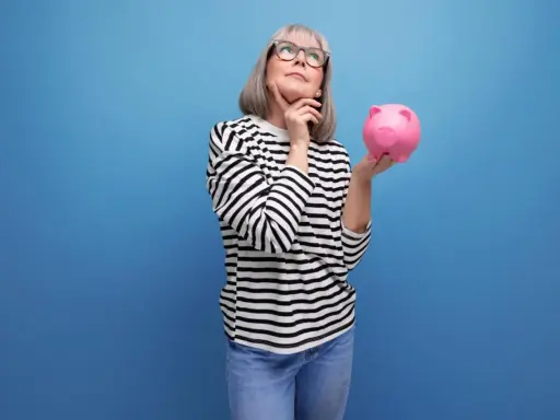 Mujer pensativa con hucha rosa, considerando los tipos de planes de pensiones para su futuro.