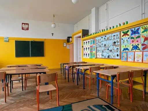 Pusta klasa z kolorowymi pracami dzieci na ścianie. Idealne miejsce, kiedy wolne od szkoły, by poczuć się jak uczeń.