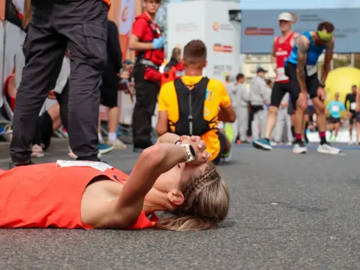Zmęczona biegaczka leży na ziemi po tym, jak dowiedziała się, ile biegnie się maraton.