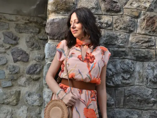 Donna con abito floreale rosa antico, cinturone marrone e borsa rotonda. I colori vivaci del vestito sono perfetti per abbinare al rosa antico.