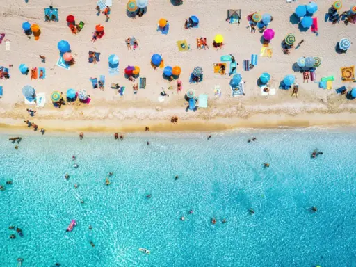 Un'affollata spiaggia di Rimini mare, con ombrelloni colorati e bagnanti che si godono il sole e il mare cristallino.