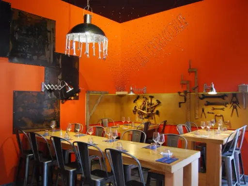 Ambiance industrielle dans un des restaurants de Chambray-lès-Tours. Tables dressées, murs orange vif, luminaires originaux.