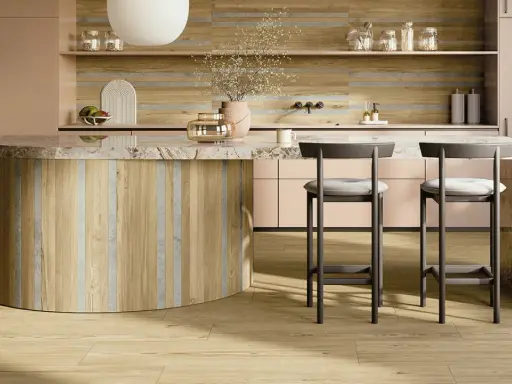 Interni di una casa super moderna: isola cucina in legno e marmo, sgabelli grigi, mobili rosa cipria e pavimento in parquet chiaro.