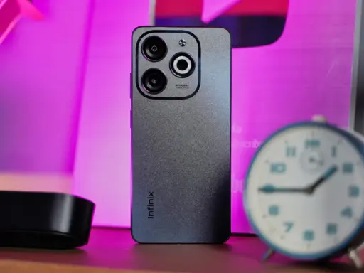 Szary smartfon Infinix z potrójnym aparatem na tle różowego światła. Czy to Infinix co to za firma?