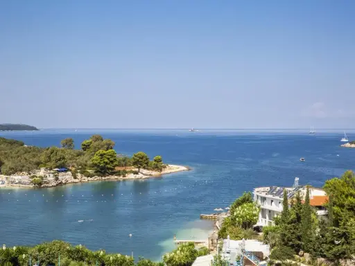 Piękna zatoka w Ksamil, Albania, z turkusową wodą, zielonymi wyspami i białym hotelem. Idealne miejsce na wakacje.