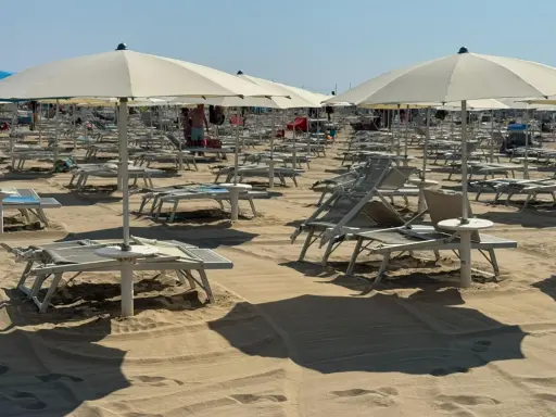 Ombrelloni e lettini pronti per il Ferragosto sulla Riviera Romagnola. La sabbia dorata attende i bagnanti.