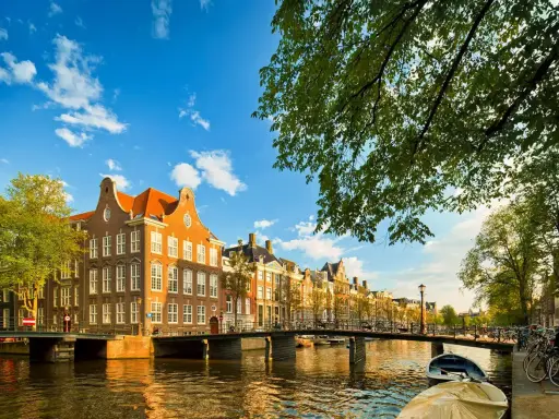 Un paseo por los canales de Amsterdam con adolescentes, disfrutando de las casas históricas y el sol.