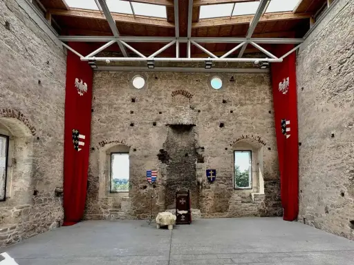 Wnętrze zamku w Szydłowie. Czerwone banery z orłami i herbami, tron. Sprawdź cennik zwiedzania!