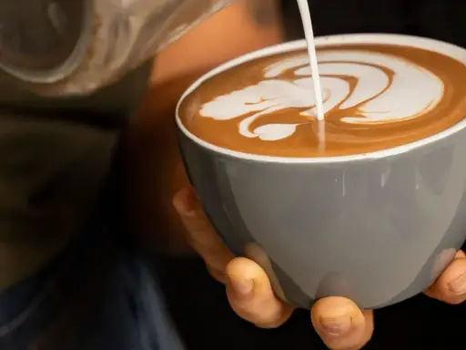 Barista verziert einen Espresso Latte mit Milchschaum. Ein Kunstwerk in der Tasse.