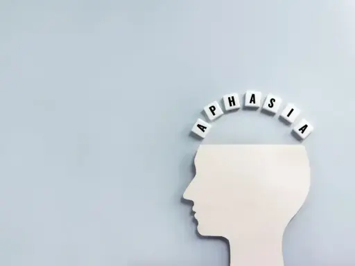 Biały profil głowy z literami tworzącymi łuk nad nią. Litery układają się w słowo "APHASIA", symbolizując afazję motoryczną.