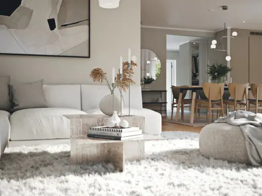 En modern lounge med en vit soffa, ett soffbord i sten och en fluffig matta. I bakgrunden syns en matsal med trästolar, vilket visar olika inredningsstilar.