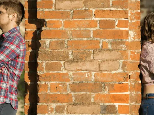 Un homme et une femme se tiennent de part et d'autre d'un mur de briques. Peut-on fixer quelque chose sur un mur mitoyen ?