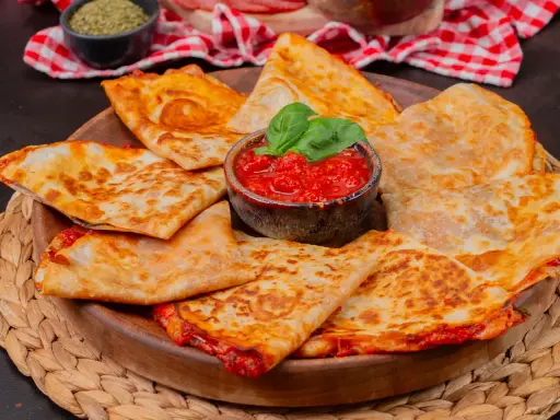 Goldbraune Quesadillas, gefüllt mit geschmolzenem Käse und Tomaten, serviert mit frischem Basilikum. Ein einfaches Quesadillas Rezept für jeden Anlass.