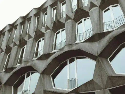 Fassade eines Gebäudes im Stil der brutalismus architektur mit geometrischen Betonformen und vielen Fenstern.