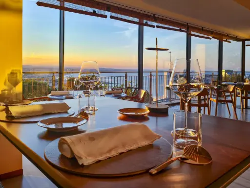 Tavola apparecchiata in un ristorante stellato a Gabicce Monte, con vista sul tramonto sul mare.