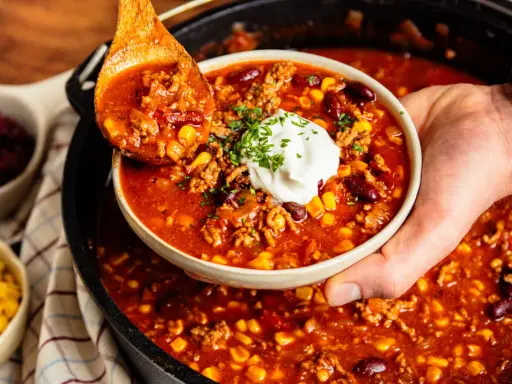 Herzhaftes Chili con Carne aus dem Dutch Oven, serviert mit einem Klecks Sour Cream und frischer Petersilie.