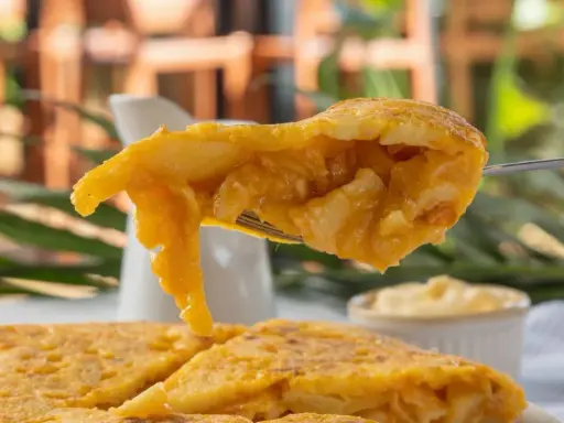 Un tenedor levanta un trozo jugoso de tortilla de espaguetis, mostrando su interior dorado y tierno.