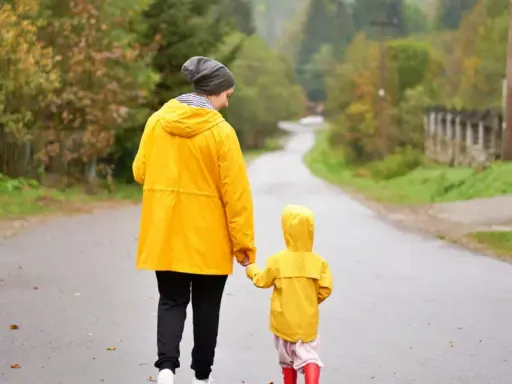 Mama i dziecko w żółtych płaszczach idą drogą. Nawet w deszczową pogodę Jastrzębia Góra oferuje atrakcje na niepogodę, jak wspólne spacery.