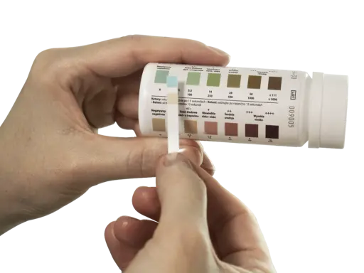 Pasek testowy do badania moczu, pokazujący obecność ketonów. Kolor paska wskazuje na poziom acetonu w moczu.