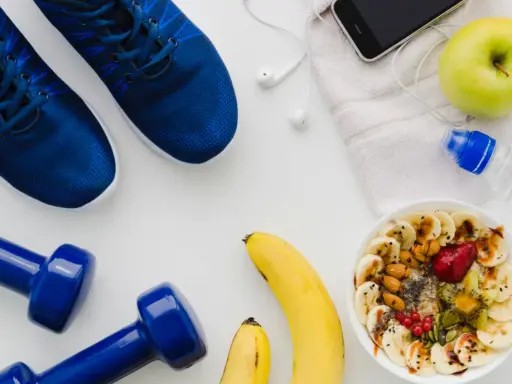 Gesunde Ernährung vor dem Halbmarathon: Haferflocken mit Früchten, Bananen, Apfel, Wasser und Sportutensilien.