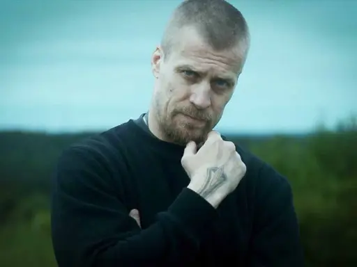 Jens Hultén, känd från filmer och tv-program, med en intensiv blick och en tatuering på handen.