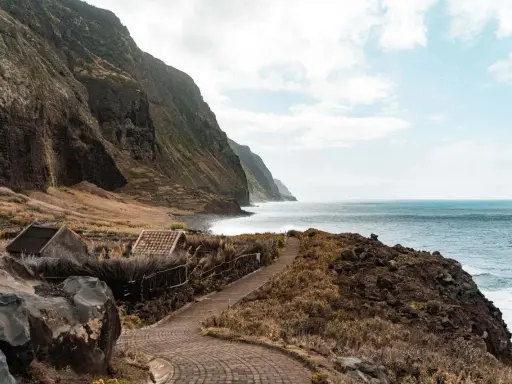 Steile Klippen, das Meer und kleine Häuser – ein **Madeira must see**! Ein Weg führt entlang der Küste.