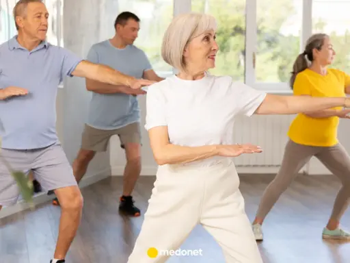 Seniorzy ćwiczą tai chi na krześle, poprawiając równowagę i spokój.