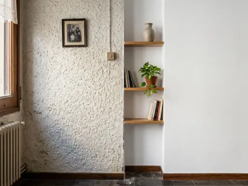 Un rincón con un radiador antiguo, un cuadro familiar y estanterías. La textura de la pared es rugosa, pero merece la pena quitar el gotelé para un acabado más liso.