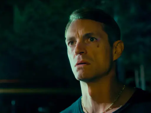 Joel Kinnaman i en mörk, intensiv scen från sin nya serie. Hans blick är fäst på något utanför bild, full av oro och beslutsamhet.