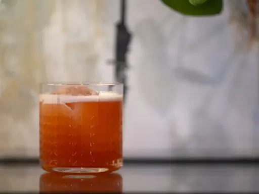 Ein erfrischender Jungle Bird Cocktail mit Eis und Schaum in einem Glas mit Rautenmuster.