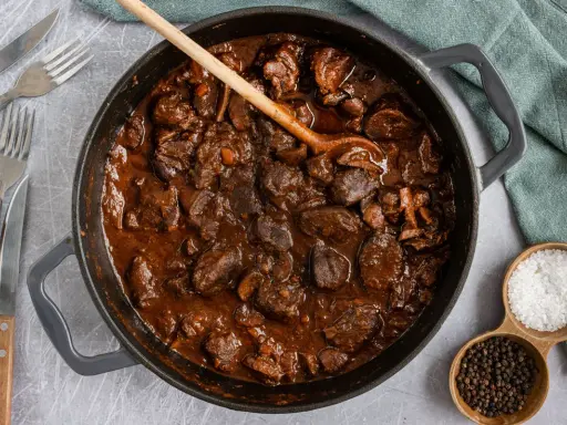 Herzhafter Rehgulasch in dunkler Sauce, bereit zum Schmoren. Die Frage "reh gulasch wie lange schmoren" wird hier visuell beantwortet: lange und langsam für zartes Fleisch.