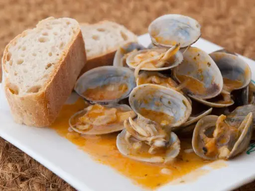 Almejas a la marinera, jugosas y sabrosas, servidas con pan rústico para mojar en la deliciosa salsa.