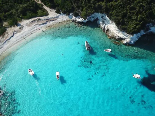 Idealne wakacje na Paxos: turkusowa woda, białe skały i łodzie unoszące się na falach.
