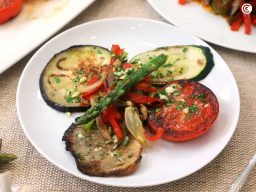 Deliciosa parrillada de verduras con berenjena, calabacín, tomate, pimientos y espárragos, todo aderezado con ajo y perejil.
