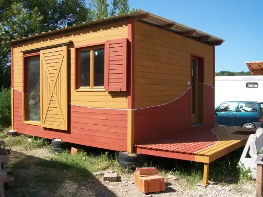 Maisonnette en bois aux couleurs vives, rappelant un nuancier peinture suédois. Porte coulissante jaune, volets rouges.