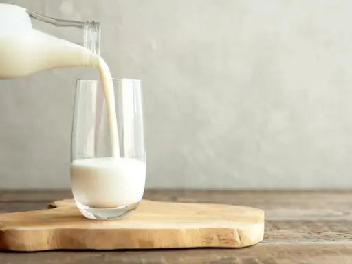 Kefir jest lekkostrawny, co widać na zdjęciu, gdy biały napój jest przelewany z butelki do szklanki.