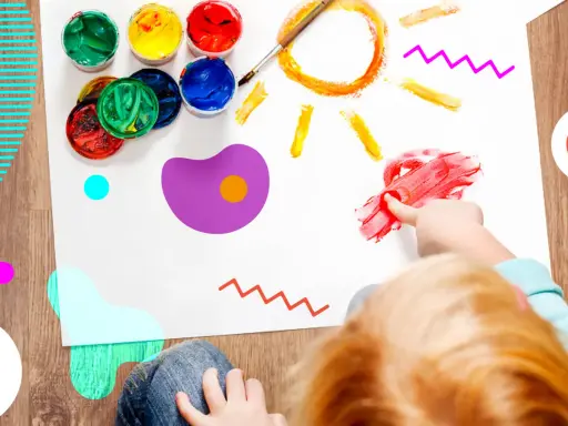 Bambino dipinge un sole con le dita, circondato da vasetti di colori. Un esempio di giochi popolari per bambini che stimolano la creatività.