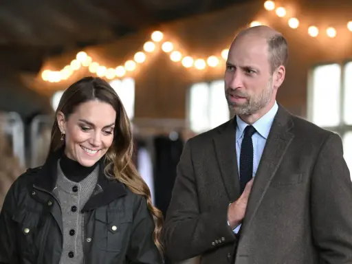 Prins William av Wales och Kate Middleton ler under en ljusslinga.