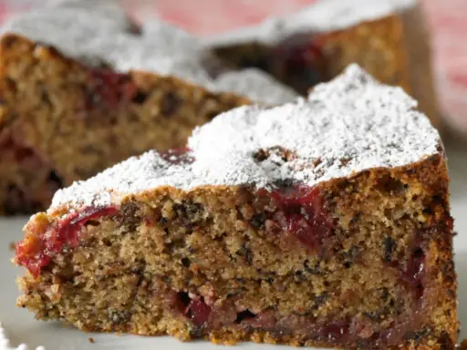 Ein saftiges Stück Buchweizentorte mit Preiselbeeren, bestäubt mit Puderzucker.